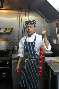 Chef holding Tandoori Chicken in the kitchen of Chillis Indian restaurant in Nottingham